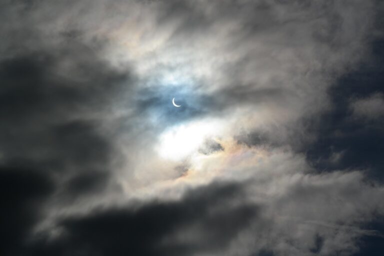 A solar eclipse partially covering the sun in a cloudy sky